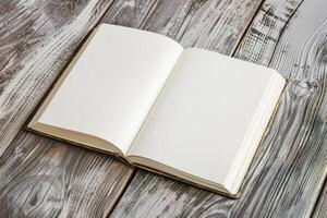 A single, blank book with a plain cover, sitting open on a wooden table under a single light source.